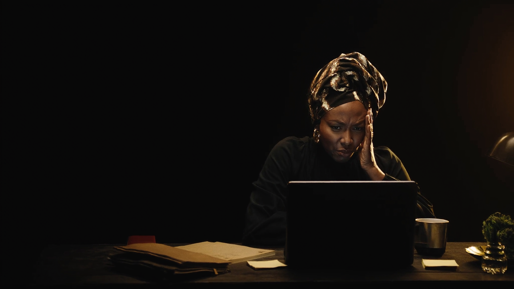 A founder at her desk late at night, one hand to her temple, frustrated at her laptop